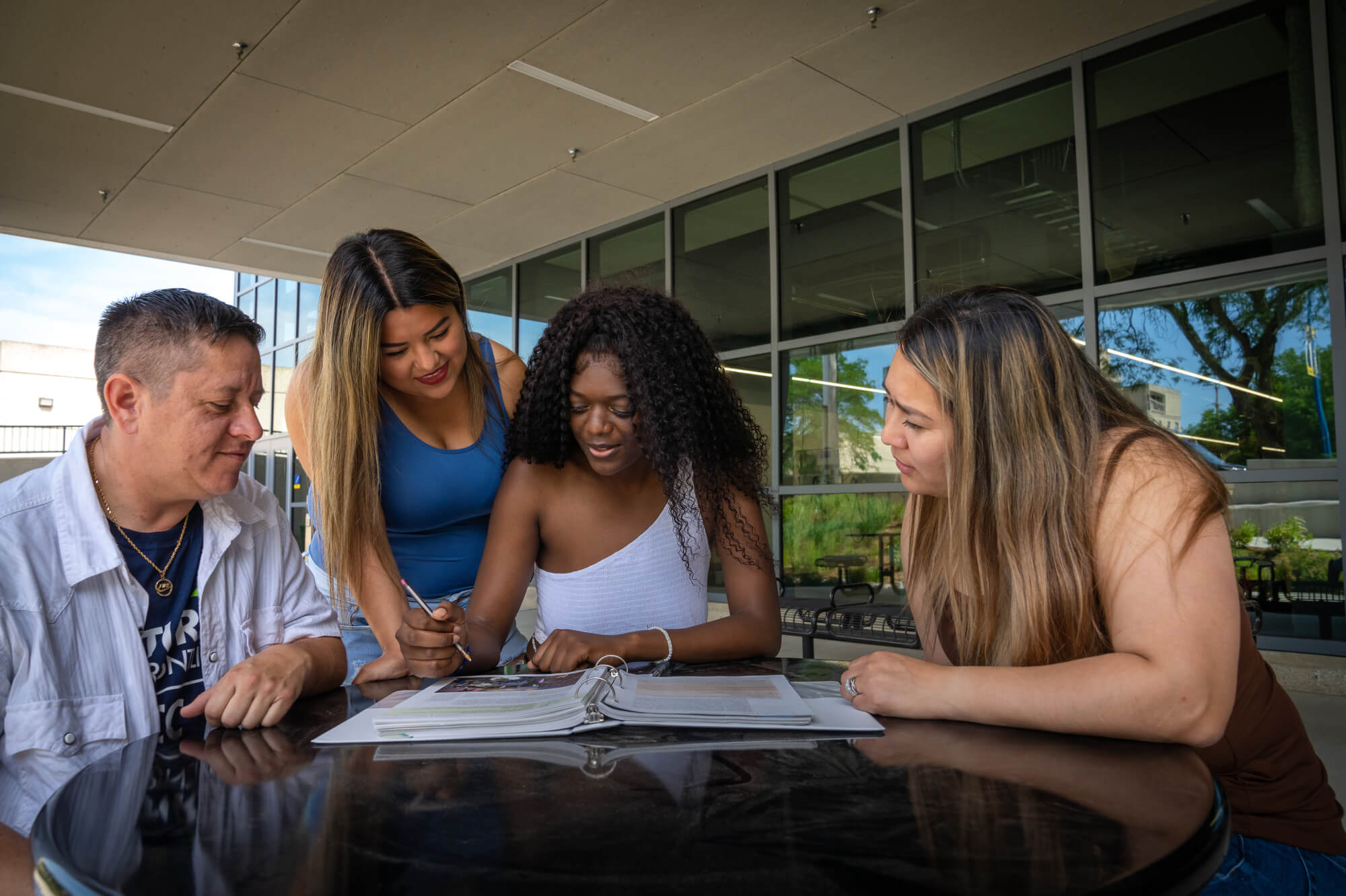 Four diverse students huddled around a table